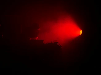 Artistic shot of LED screens and stage equipment glowing softly in dark tones with red highlights.