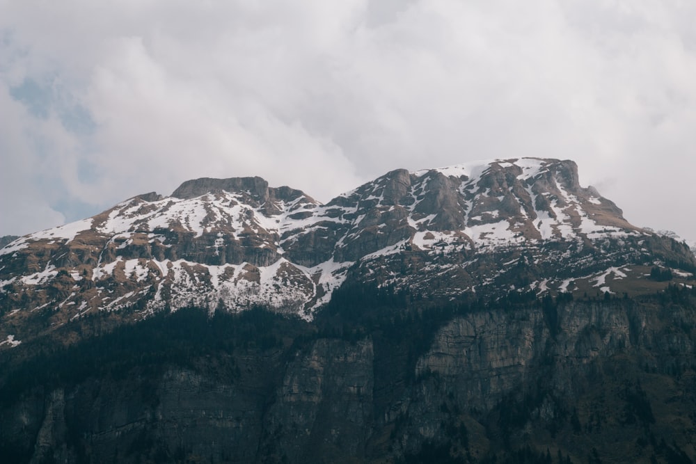 a mountain covered in snow under a cloudy sky