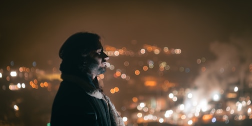 Close-up of a model wearing a sleek Lumina Apparel jacket with city skyline in background.