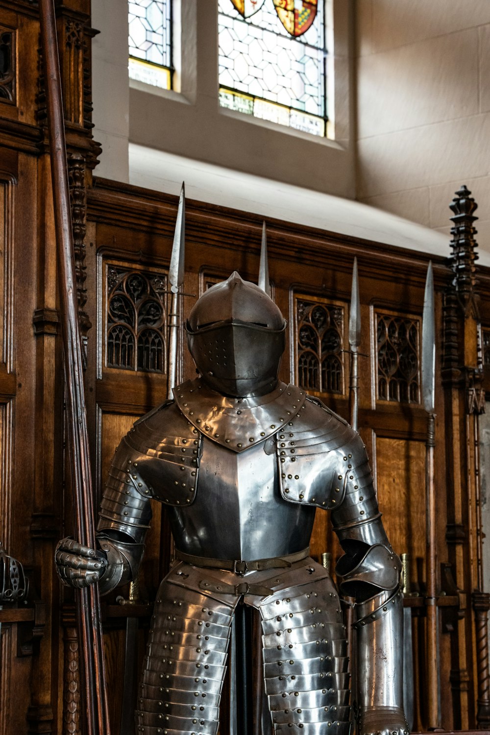 a statue of a knight holding a sword in front of a stained glass window