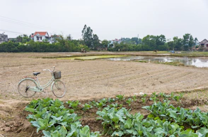 a bike parked next to a plowed field