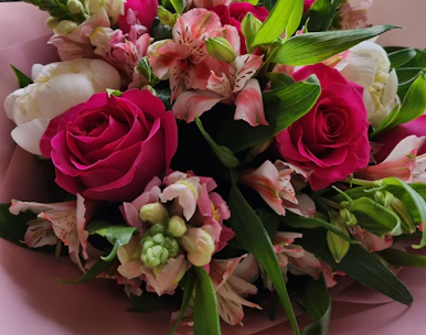 A lush bridal bouquet of ivory roses and soft pink peonies wrapped in gold ribbon.