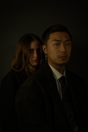A sophisticated portrait of a couple dressed in designer attire, illuminated by cinematic lighting in a minimalist studio.