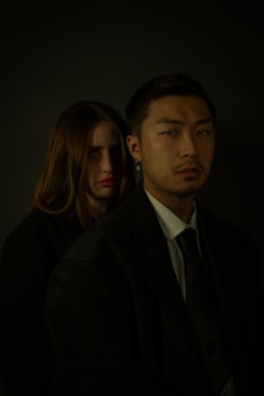 A sophisticated portrait of a couple dressed in designer attire, illuminated by cinematic lighting in a minimalist studio.