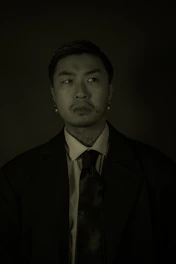 Professional portrait of Riky Aprianto in formal attire with navy and gold accents, set against a Palu city backdrop.