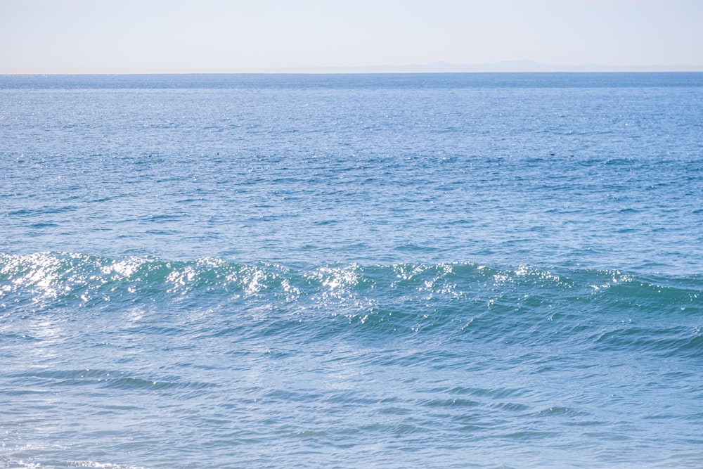 una persona montando una tabla de surf en una ola en el océano