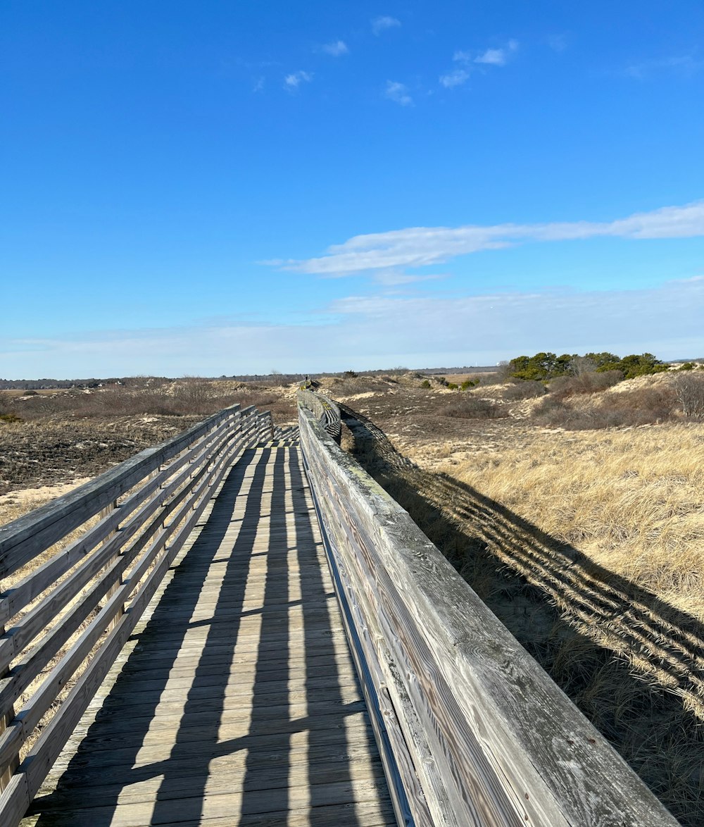 a long wooden bridge over a dry grass field