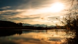 A serene landscape with mountains reflecting in a calm lake at sunrise.