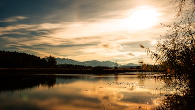 A serene landscape with mountains reflecting in a calm lake at sunrise.