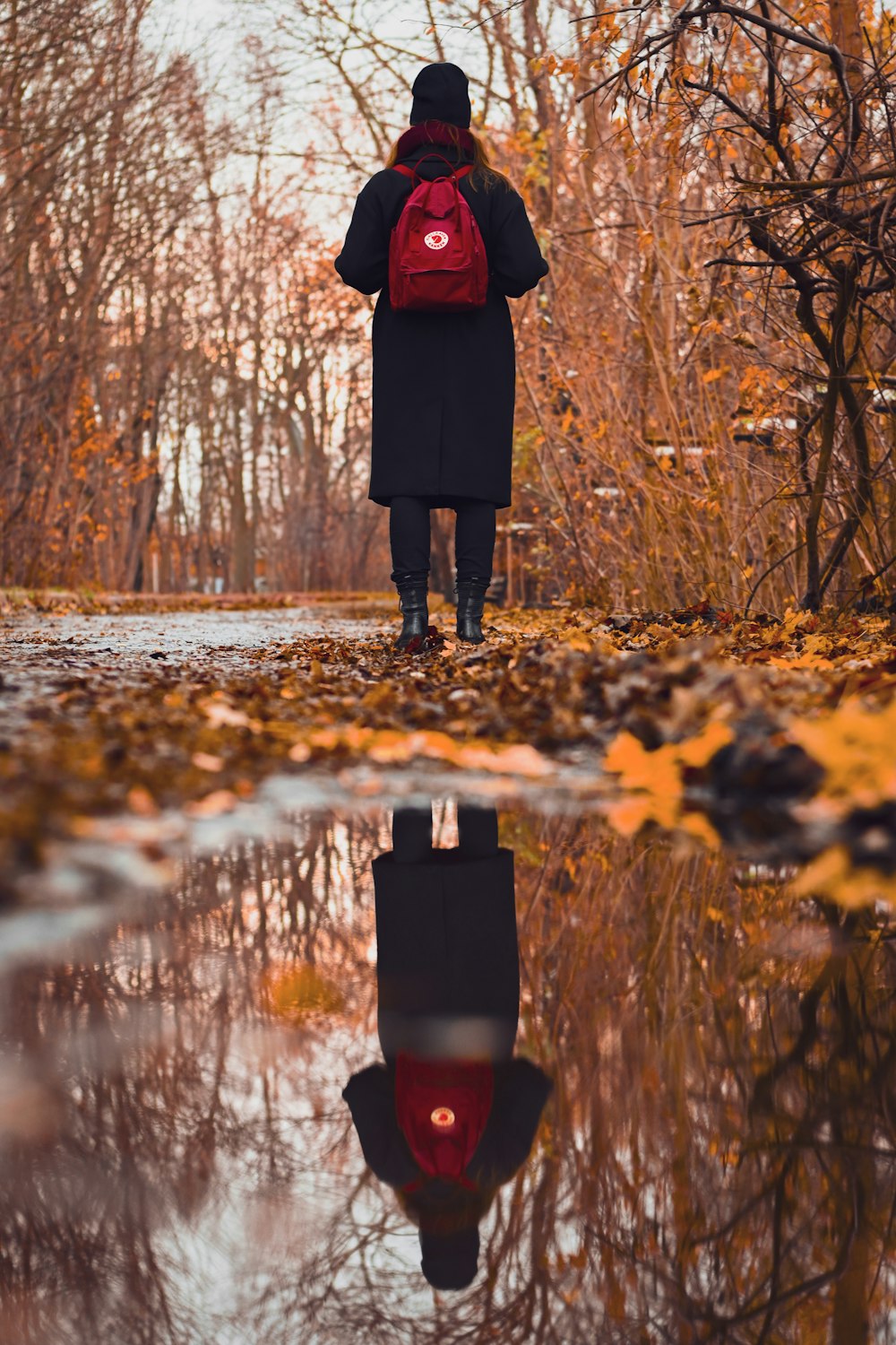 a woman with a red backpack is walking through the woods