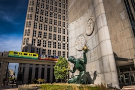 a statue in front of a building with a train passing by