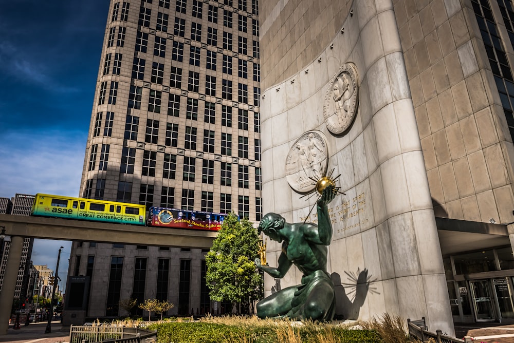 a statue in front of a building with a train passing by