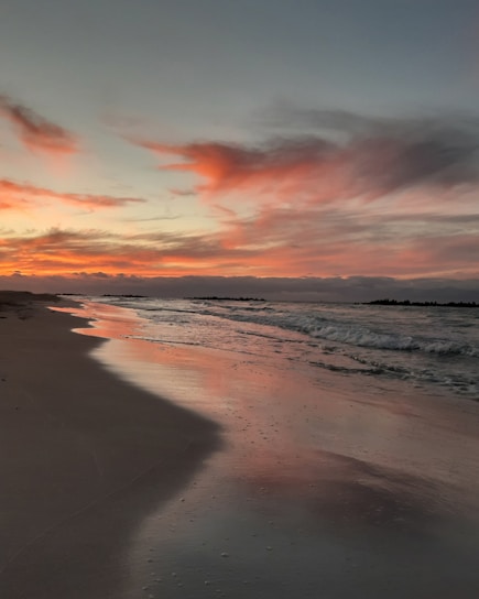 A romantic sunset over the beach at Buenavista, Los Cabos, with soft waves and warm colors.
