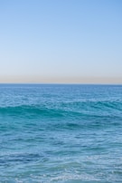 A peaceful seaside view with gentle waves and a hint of blue ocean blending into the horizon.