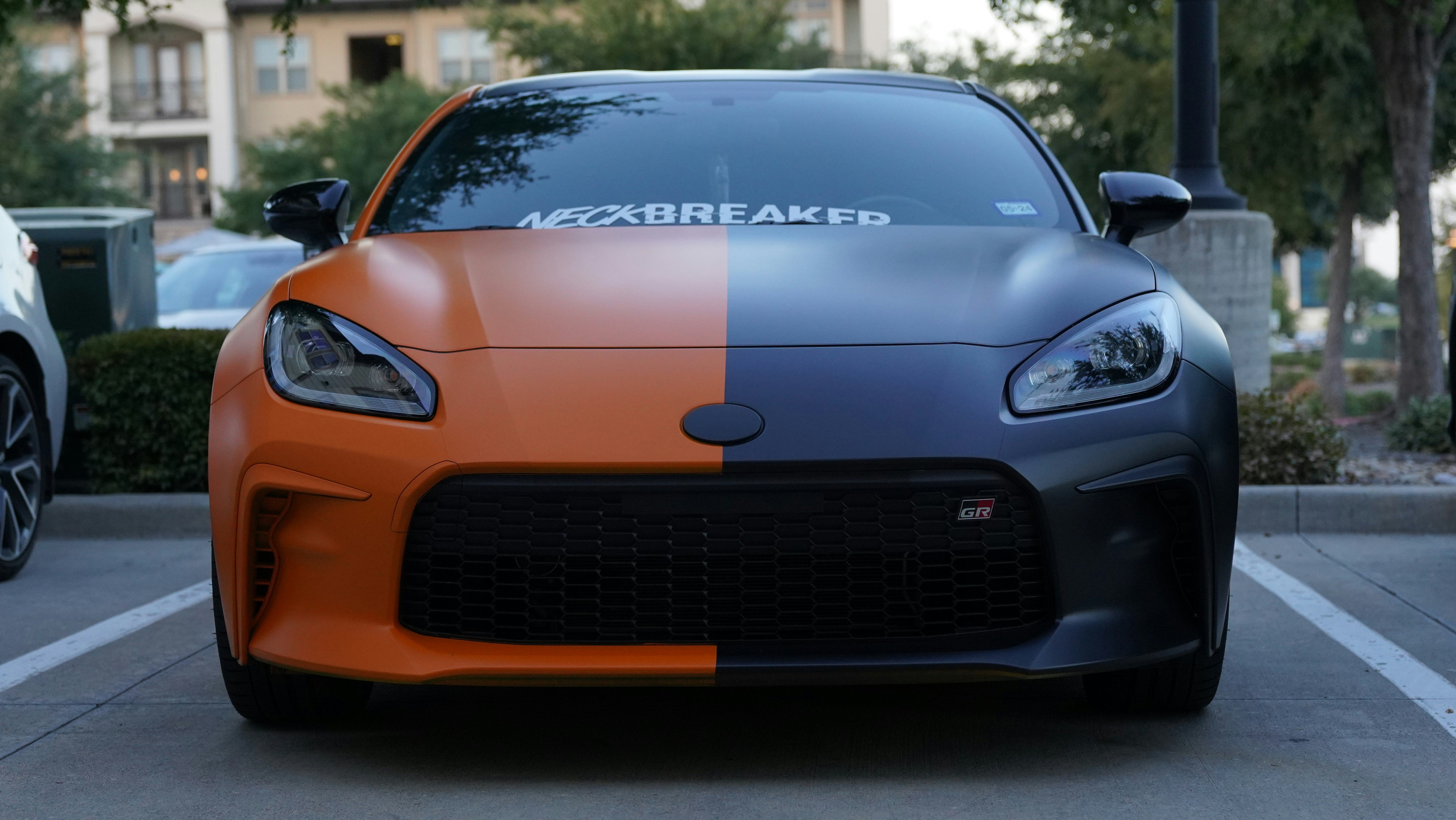 an orange and black sports car parked in a parking lot