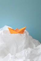 Close-up of hands folding a bright origami boat.