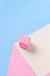 a pink origami object on a blue and pink background