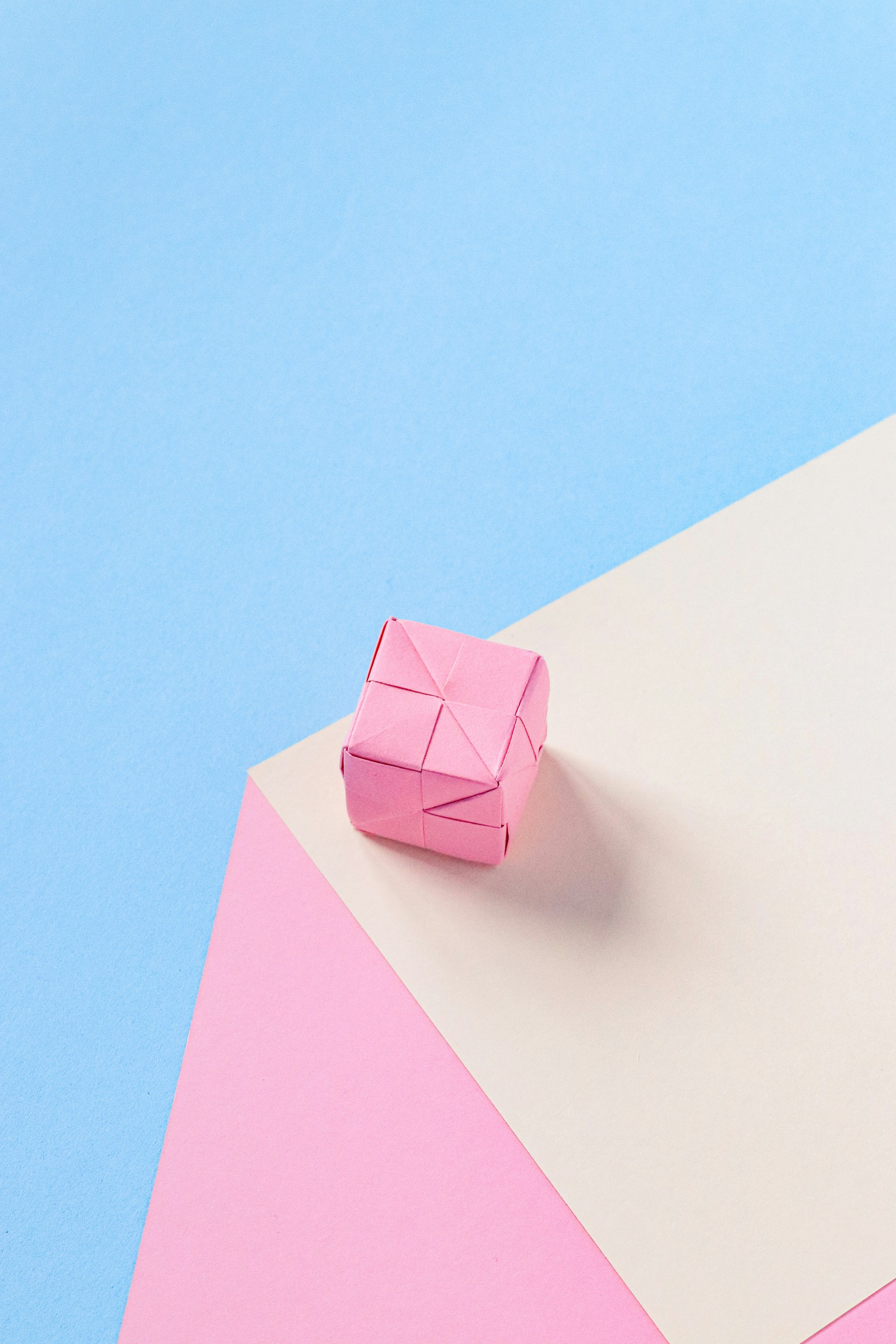 a pink origami object on a blue and pink background