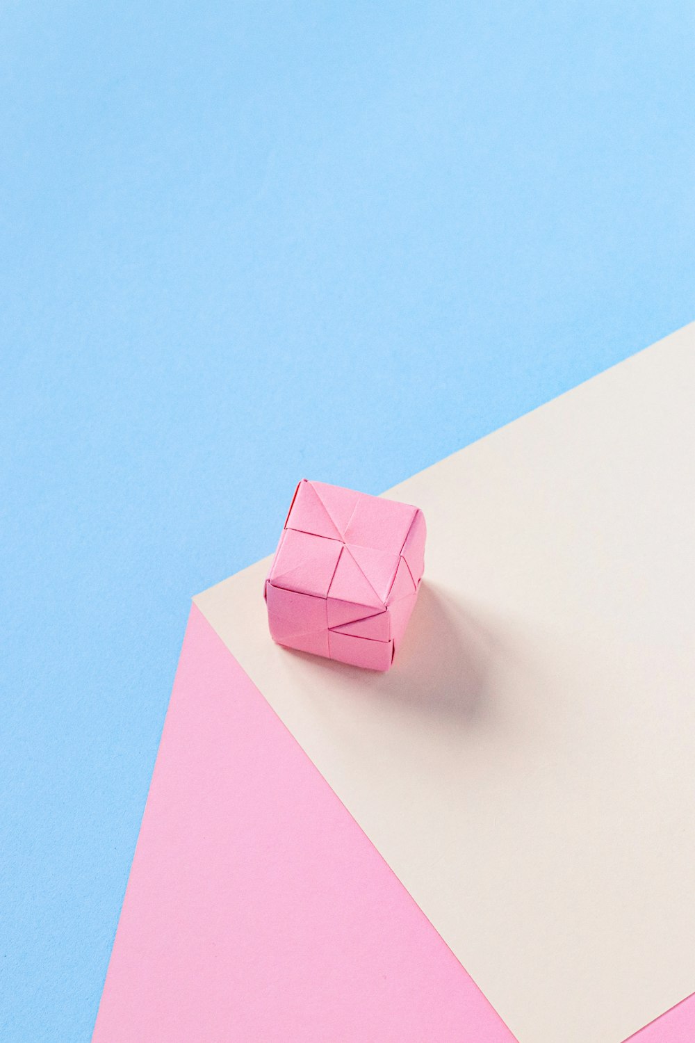 a pink origami object on a blue and pink background
