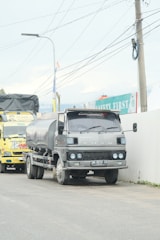 A heavy-duty truck carrying bulk fertilizer tanks parked at a rural farm site.