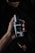 A hand holding a dark, sleek bottle of perfume labeled 'Sauvage' by Dior. The background is dark and creates a moody, sophisticated atmosphere.