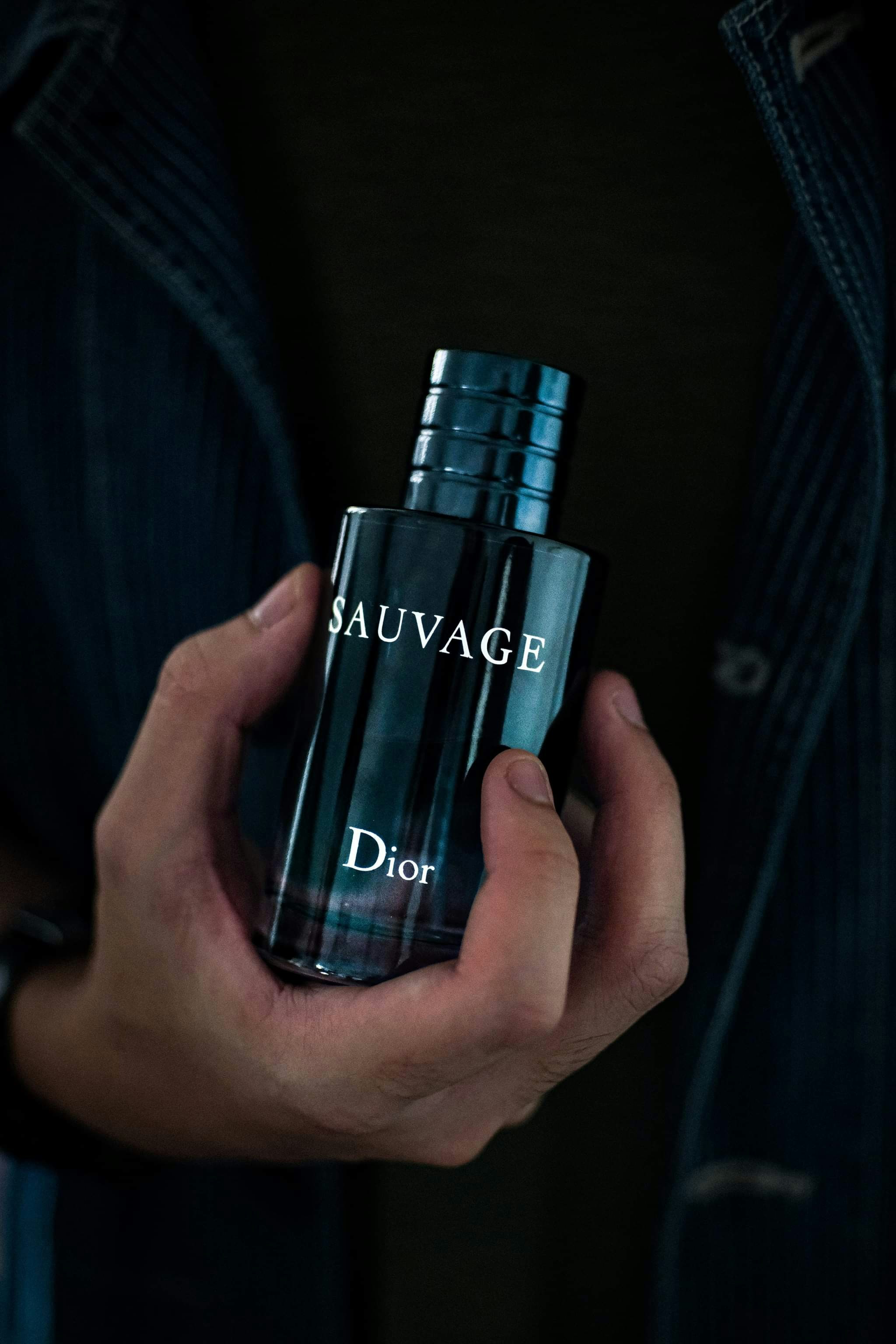 Un homme tenant une bouteille de Dior Sauvage