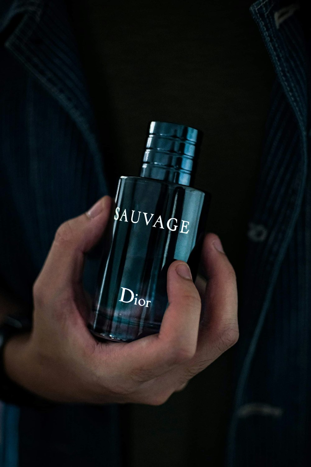 a man holding a bottle of dior sauvage