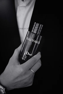 Monochromatic image of a man applying parislawn cologne in a softly lit modern bathroom setting