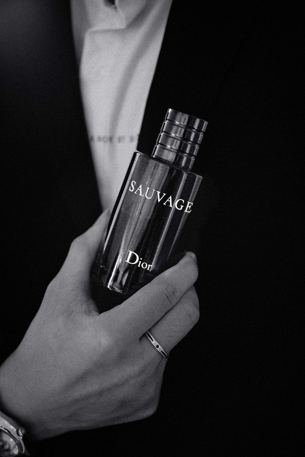 a man in a suit holding a bottle of perfume
