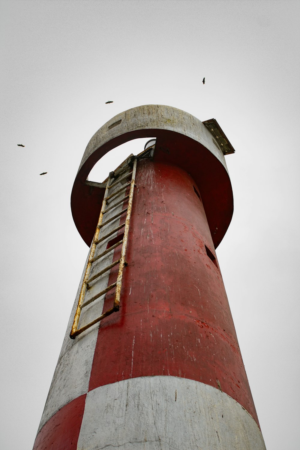 a red and white lighthouse with a ladder