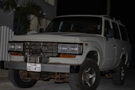 A Sugob Security Services Toyota Land Cruiser stationed outside a government institution under bright daylight.