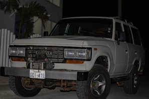 A Toyota Fortuner gleaming under natural light, parked near a bustling city street in Conakry.