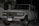 A white Toyota SUV is parked outdoors during the evening or night. The vehicle's front grille and headlights are clearly visible. It has a front-mounted license plate from Ecuador with the number GDI-419, and the front bumper appears robust. There are some palm leaves and a modern building in the background.