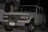 A white Toyota SUV is parked outdoors during the evening or night. The vehicle's front grille and headlights are clearly visible. It has a front-mounted license plate from Ecuador with the number GDI-419, and the front bumper appears robust. There are some palm leaves and a modern building in the background.