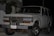 A white Toyota SUV is parked outdoors during the evening or night. The vehicle's front grille and headlights are clearly visible. It has a front-mounted license plate from Ecuador with the number GDI-419, and the front bumper appears robust. There are some palm leaves and a modern building in the background.
