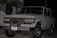 A white Toyota SUV is parked outdoors during the evening or night. The vehicle's front grille and headlights are clearly visible. It has a front-mounted license plate from Ecuador with the number GDI-419, and the front bumper appears robust. There are some palm leaves and a modern building in the background.