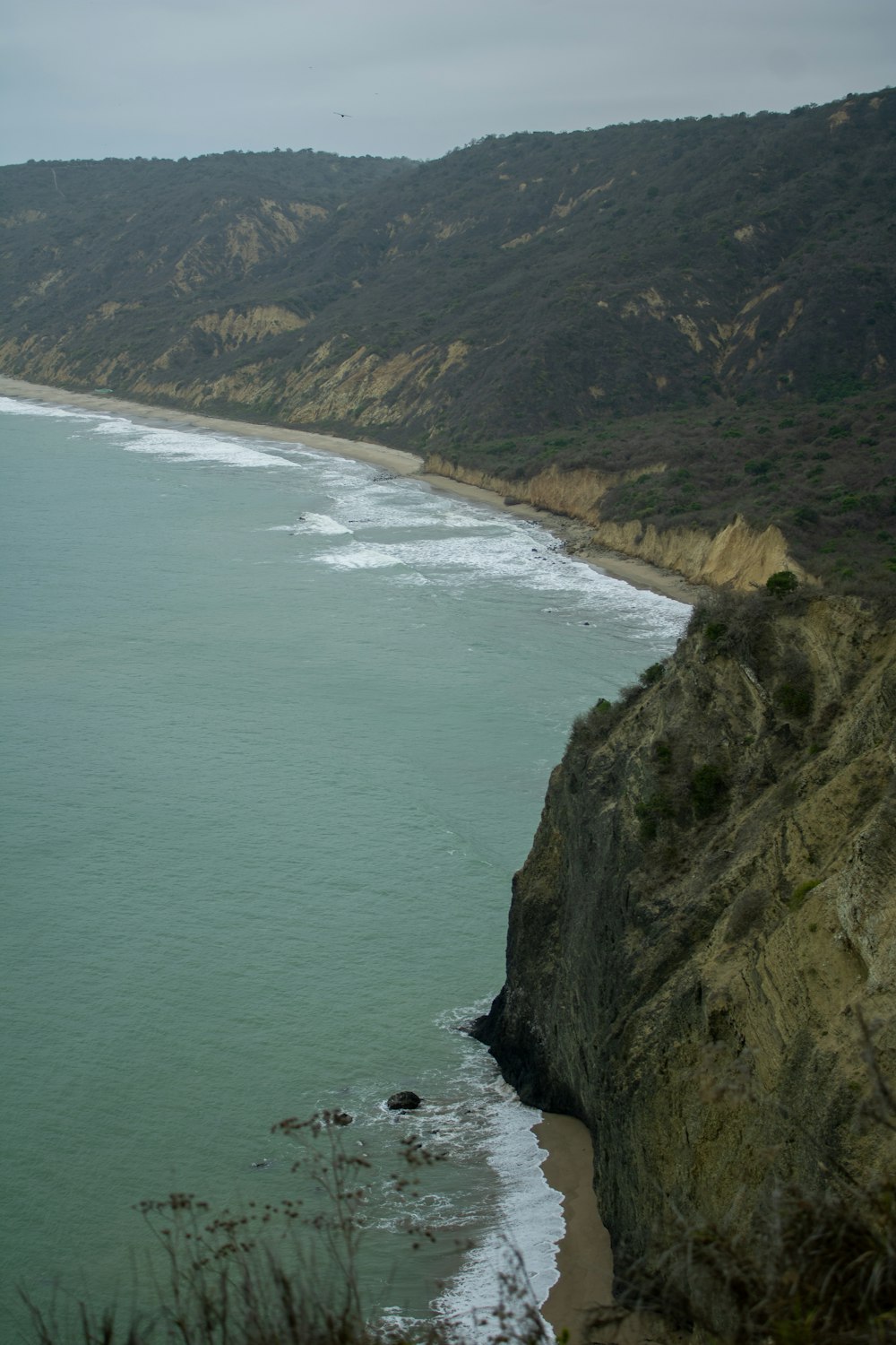 a large body of water sitting next to a lush green hillside