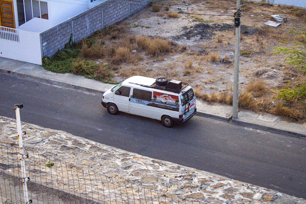 a white van driving down a street next to a tall building