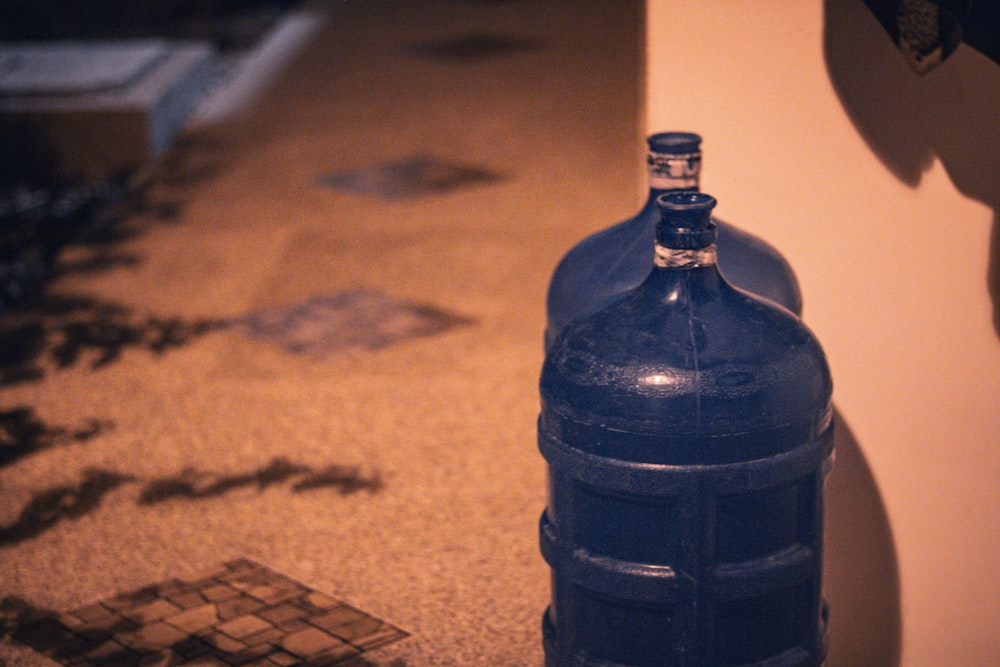 una bottiglia blu seduta sul pavimento accanto a un muro