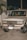 A white Toyota SUV with an Ecuadorian license plate is parked on a concrete surface at night. The vehicle appears to be an older model with noticeable wear on the bumper and front grille. There is a white picket fence and some palm trees in the background.