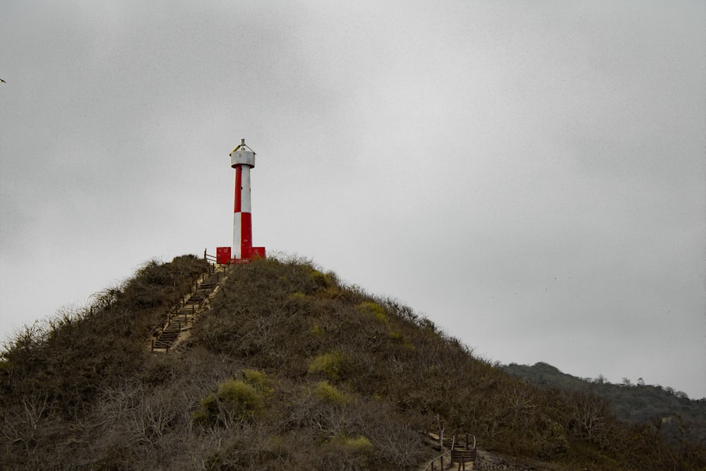 un faro rojo y blanco en la cima de una colina