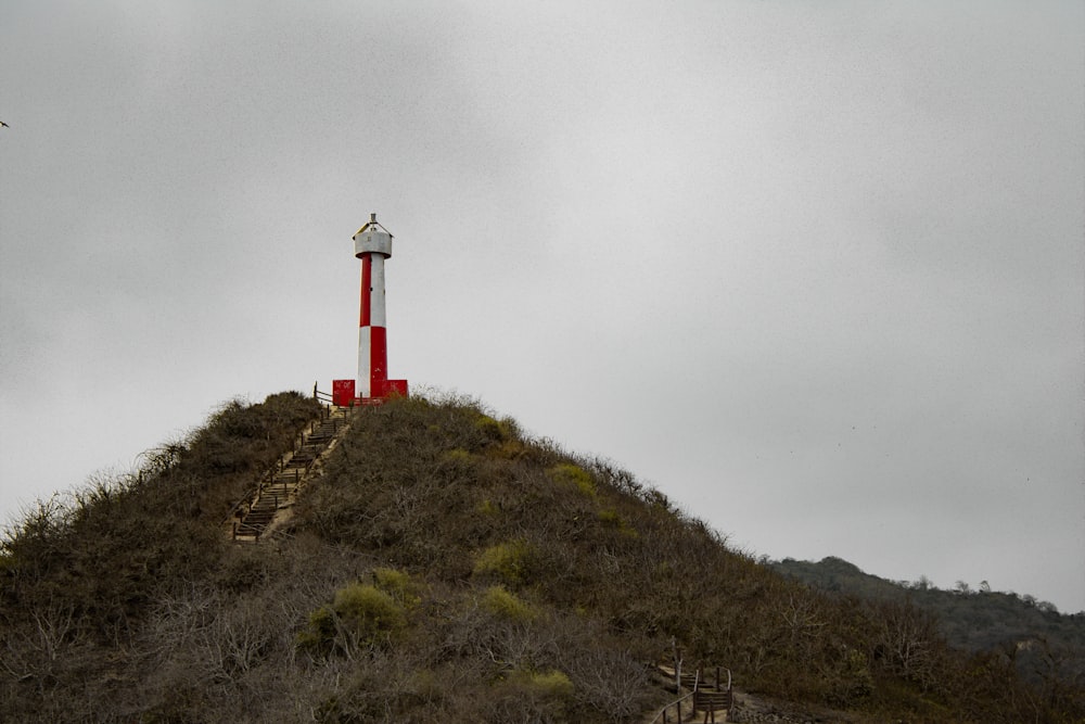 a red and white lighthouse on top of a hill