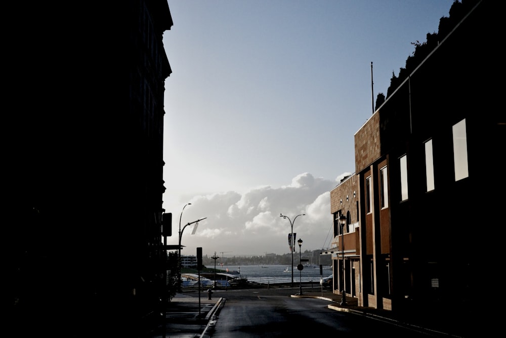 a view of a street with buildings and a body of water in the distance