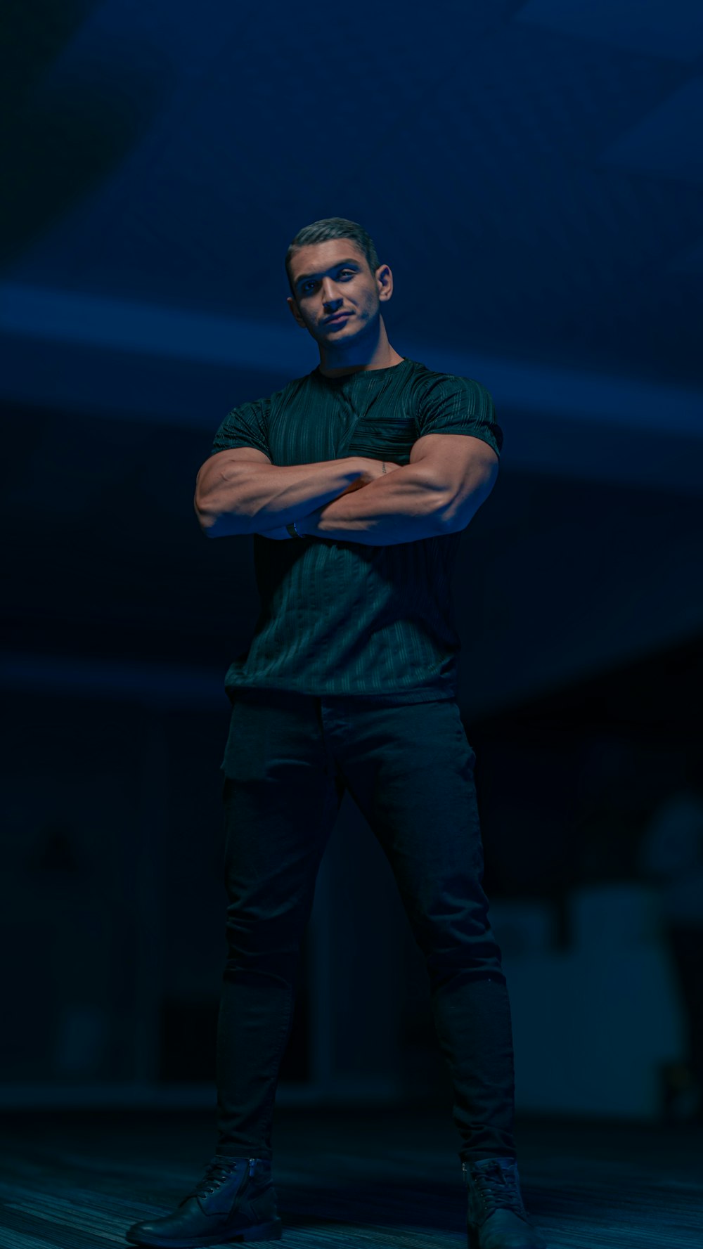 a man standing in a dark room with his arms crossed