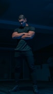 a man standing in a dark room with his arms crossed