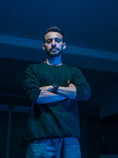 a man standing in a dark room with his arms crossed