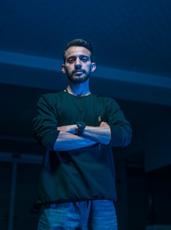 a man standing in a dark room with his arms crossed