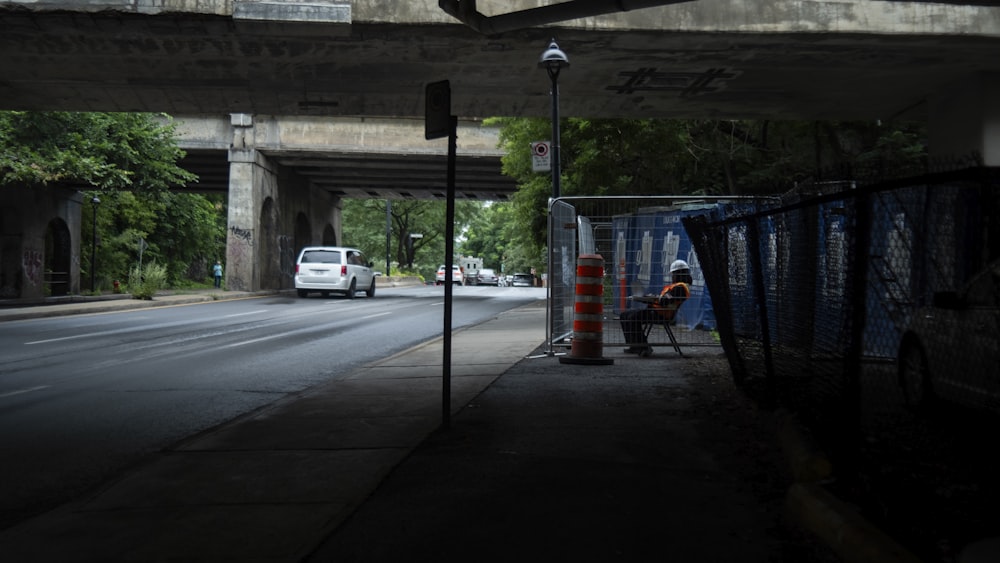 a person sitting on a bench under a bridge