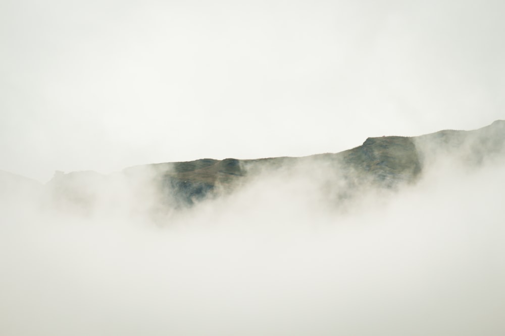 a mountain covered in fog and clouds on a cloudy day