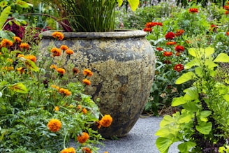 a large vase sitting in the middle of a garden filled with flowers